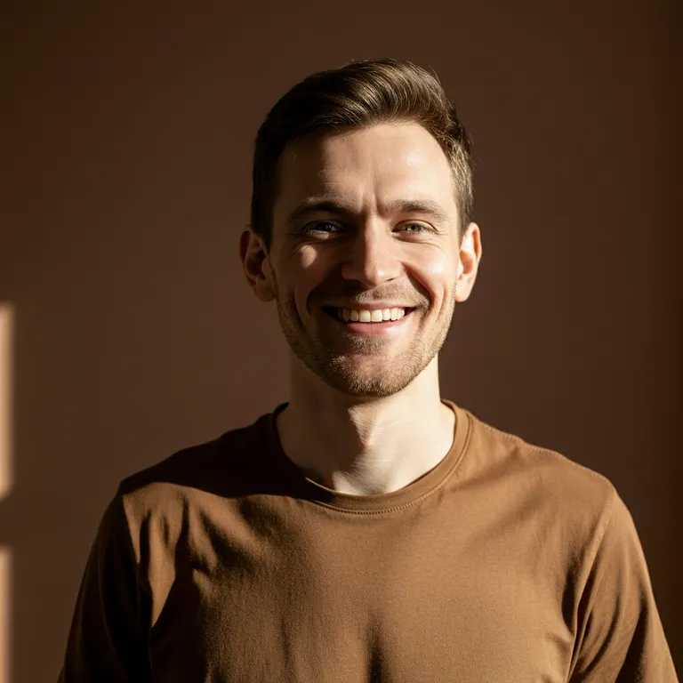 Smiling man with short brown hair wearing a brown shirt against a brown background.